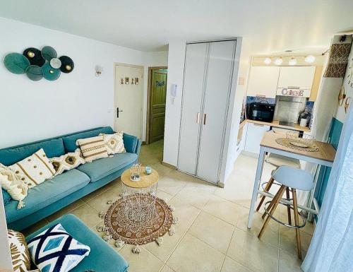 un salon avec un canapé bleu et une cuisine dans l'établissement Studio cosy et climatisé au coeur du village, à Valbonne