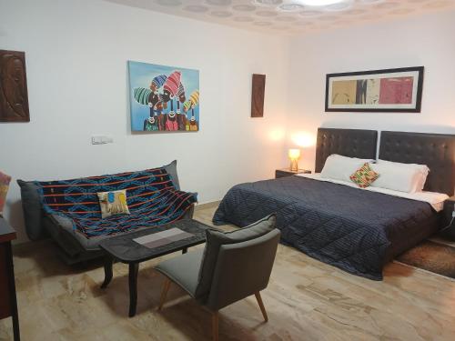 a bedroom with a bed and a table and a chair at Villa Mango in Abidjan