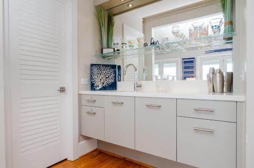 a white bathroom with a sink and a mirror at Blake Cottage by Bryant Real Estate in Wrightsville Beach