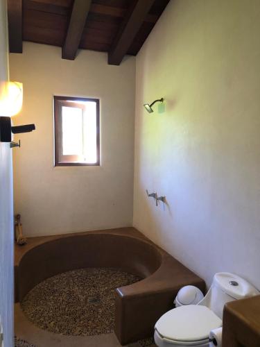 a bathroom with a bath tub and a toilet at Las Villas, Villa Alegria,Troncones in Troncones