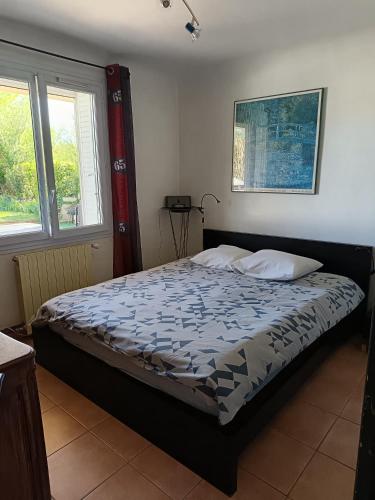 une chambre avec un lit dans une pièce avec deux fenêtres dans l'établissement Maisonnette provençale, à Courthézon