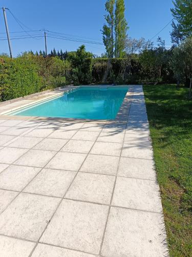 une piscine avec une allée en béton dans l'établissement Maisonnette provençale, à Courthézon
