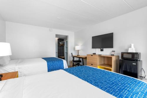 a hotel room with two beds and a flat screen tv at Atlantic Inn in Virginia Beach