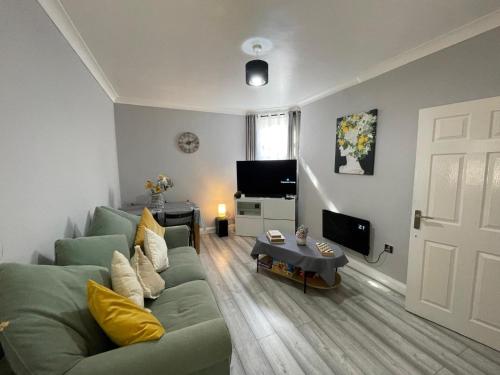 a living room with a green couch and a television at City Life Access Everywhere in London
