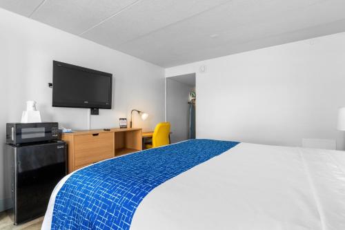 a hotel room with a bed and a flat screen tv at Atlantic Inn in Virginia Beach