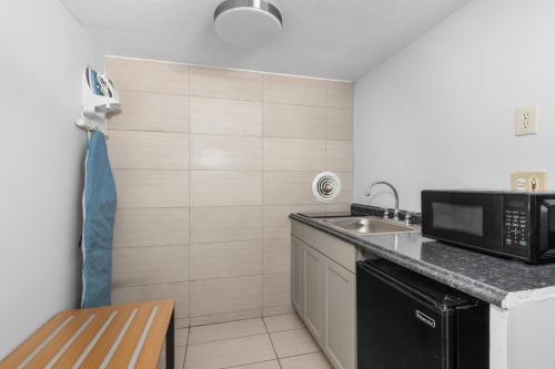 a small kitchen with a sink and a microwave at Atlantic Inn in Virginia Beach
