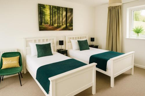 a bedroom with two beds and a green chair at Lytton Tree Lodge Near Southwold in Reydon