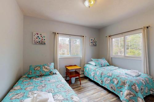 a bedroom with two beds and a table and two windows at Breezy Marie in Nameloc Heights