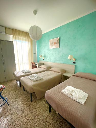 a hotel room with four beds and a blue wall at Hotel Reale in Rimini