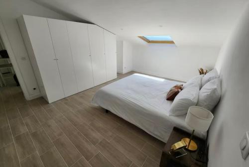 une chambre blanche avec un lit et des armoires blanches dans l'établissement T2 Sanguinaires - 150m de la mer, à Ajaccio