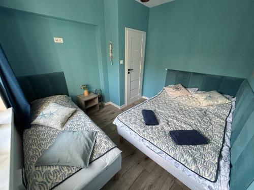 two beds in a bedroom with blue walls at Blue Apartment B, Dębina in Debina