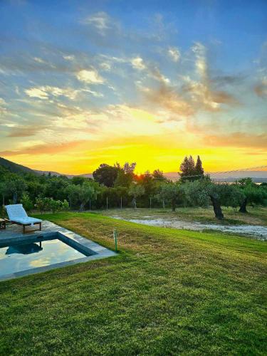 a pool in a field with a sunset in the background at NOCE Luxury Villas Resort in Vourvourou