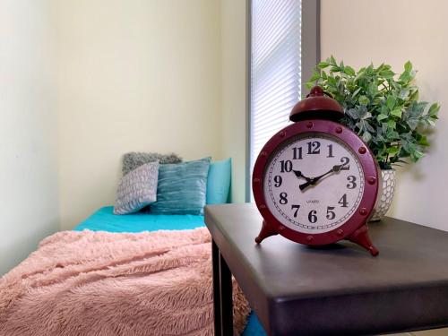 a red clock sitting on a table next to a bed at Huge 6BR Home , Modern & Convenient in Niagara Falls