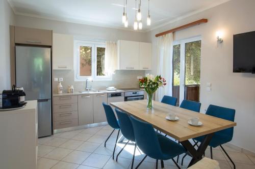 a kitchen with a wooden table and blue chairs at Evridiki's Villas in Agios Nikitas