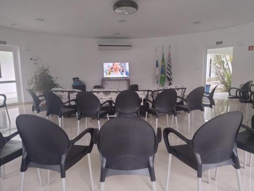a meeting room with black chairs and a television at Colônia de Férias Beleza e Arte in Caraguatatuba