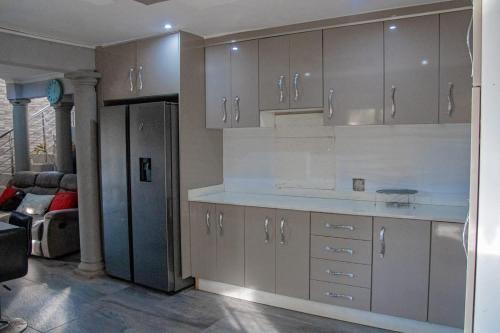 a kitchen with white cabinets and a living room at PPM BnB in KwaNgongoma