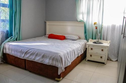 a bedroom with a bed with a red pillow and a night stand at PPM BnB in KwaNgongoma