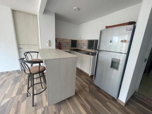 La cuisine est équipée d'un réfrigérateur et de deux tabourets de bar. dans l'établissement Acogedor apartamento, à Estación El Salto