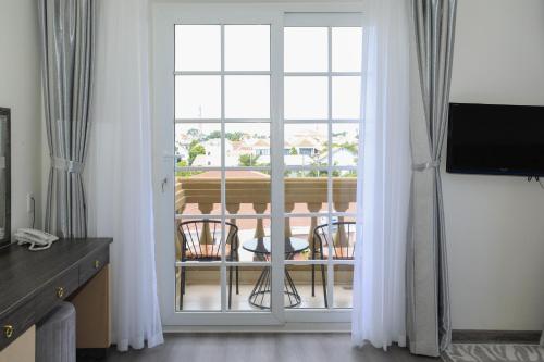 a room with a large window with chairs and a balcony at Premium CGP Hotel Hoi An in Hoi An