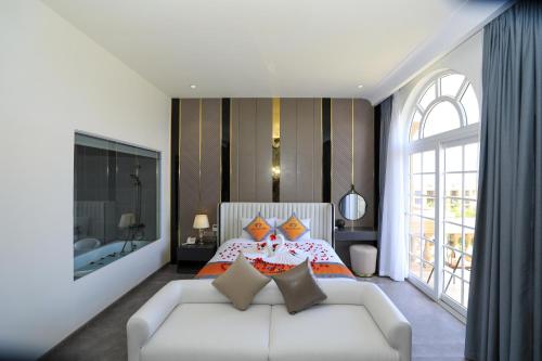 a bedroom with a bed and a white couch at Premium CGP Hotel Hoi An in Hoi An