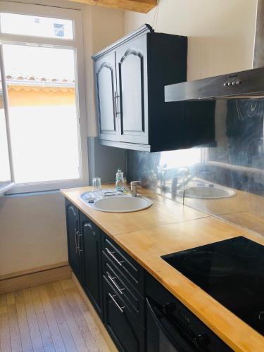 - une cuisine avec des placards noirs et un évier dans l'établissement Duplex La Ciotat - T2 - Plages & Vieux Port - climatisation, à La Ciotat