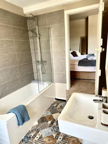 a bathroom with a shower and a tub and a sink at Moon House Crewe in Crewe