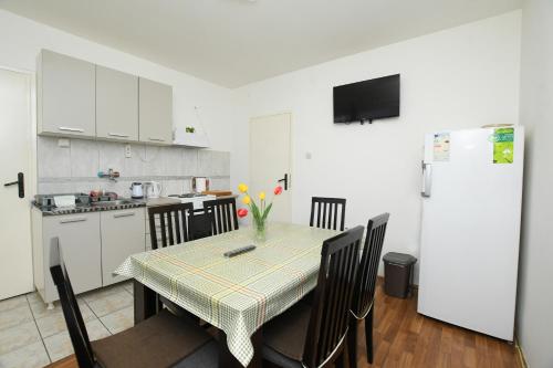 a kitchen with a table with chairs and a refrigerator at Vila Popović Plaža in Kladovo