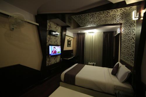 a hotel room with a bed and a television at Beverly villa in Ooty