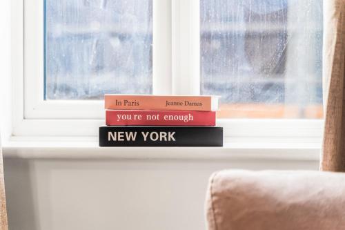 a stack of books sitting on a window sill at 247 Serviced Accommodation in Telford 4BR House in Telford