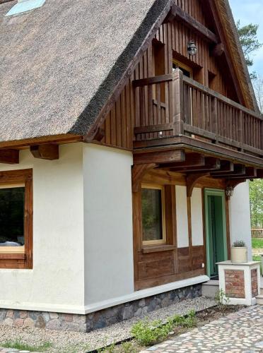 a house with a wooden roof and a balcony at Strużka Kaszuby - Leśniczówka w sercu Borów Tucholskich in Małe Swornegacie
