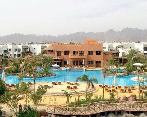un complejo con una gran piscina con mesas y sillas en Delta Sharm Casa, en Sharm El Sheikh