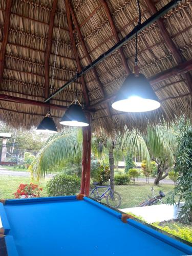 a pool table under a straw roof with lights at Hotel Boutique Victoria in Moyogalpa