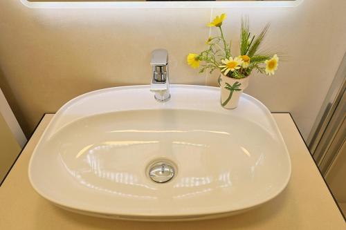 a white sink with a vase of flowers on it at Panoramico Appartamento Lido Conchiglie in Gallipoli