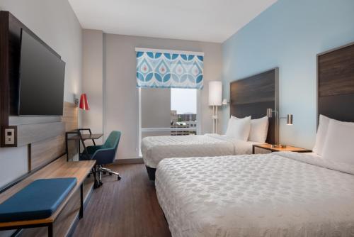 a hotel room with two beds and a flat screen tv at Tru By Hilton Houston Downtown Convention Center in Houston
