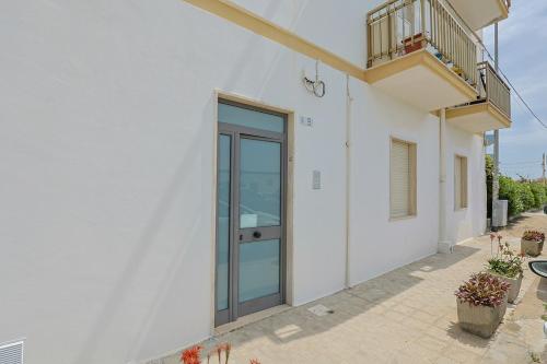 a white building with a glass door and a balcony at Panoramico Appartamento Lido Conchiglie in Gallipoli