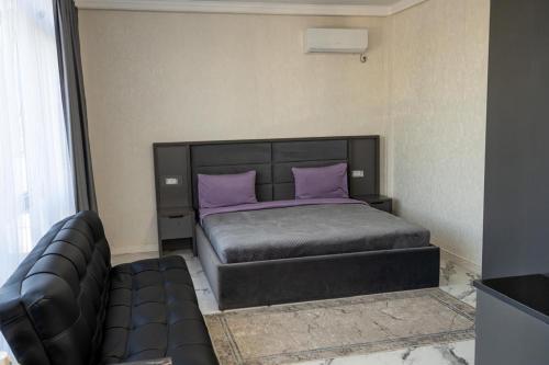 a bedroom with a bed with purple pillows and a couch at Urban Hotel in Almaty