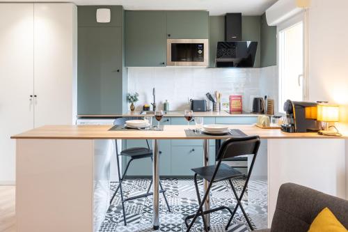 a kitchen with blue cabinets and a table with chairs at Logis Verde à 5 min de l'autoroute A10, balcon & parking privé in Châtellerault