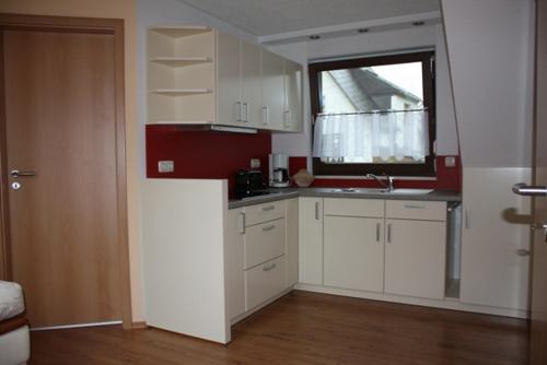 a kitchen with white cabinets and a window at Ferienwohnung am Fuße des Poehlberg in Königswalde