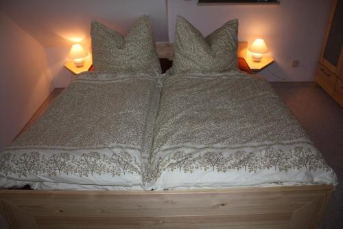a bed with a white comforter and pillows at Ferienwohnung am Fuße des Poehlberg in Königswalde