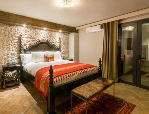 a bedroom with a king sized bed with a stone wall at Casa 1810 Hotel Boutique in San Miguel de Allende