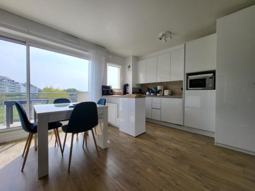 une cuisine avec des armoires blanches et une table et des chaises dans l'établissement Domaine des Roches, à Trouville-sur-Mer