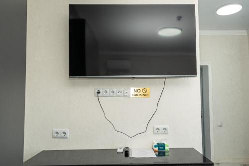 a tv on a wall with a sign on it at Urban Hotel in Almaty