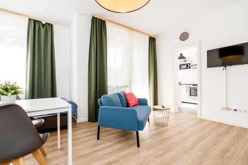 a living room with a blue chair and a desk at Centerline Apartments Solingen in Solingen
