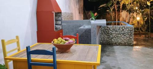 a table with a bowl of fruit and two chairs at Casa da Flor in Morretes