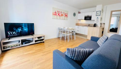 un salon avec un canapé bleu et une télévision dans l'établissement Le Mirabeau - Deauville, à Deauville