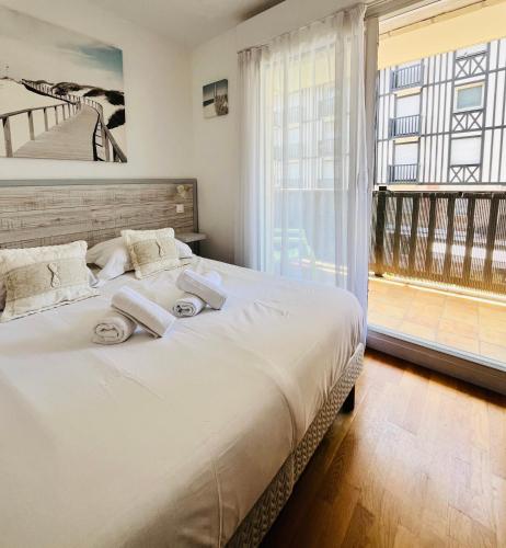 une chambre avec un lit et une grande fenêtre dans l'établissement Le Mirabeau - Deauville, à Deauville