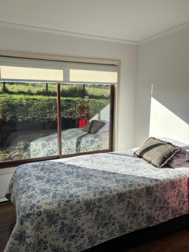 a bedroom with a bed and a large window at Casa en parcelación pichilaguna, Llanquihue in Llanquihue