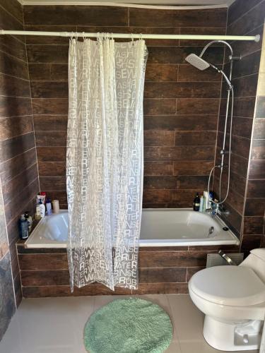 a bathroom with a tub and a toilet and a shower curtain at Casa en parcelación pichilaguna, Llanquihue in Llanquihue