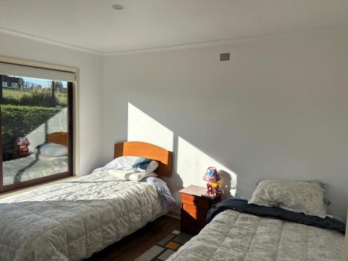 a bedroom with two beds and a window at Casa en parcelación pichilaguna, Llanquihue in Llanquihue
