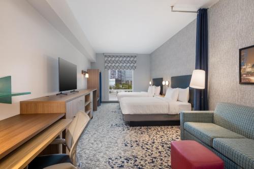 ヒューストンにあるHome2 Suites By Hilton Houston Downtown Convention Centerのベッドとテレビがあるホテルの部屋